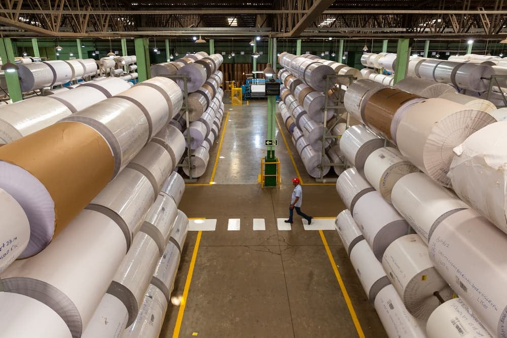 Rolos de papel armazenados em fábrica com materiais provenientes de fontes responsáveis e certificado FSC.