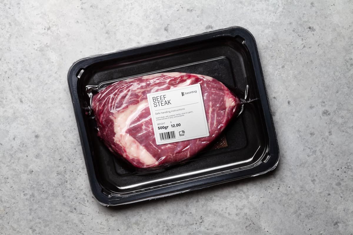 Vacuum-sealed beef steak in a black plastic tray with a Beontag security and product label on top, including weight, price, and handling instructions.
