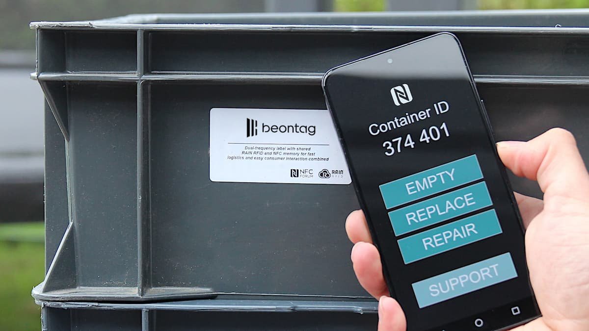 Hand holding a smartphone displaying a “Container ID” screen next to a plastic crate labeled Beontag, illustrating RFID/NFC-enabled inventory tracking.
