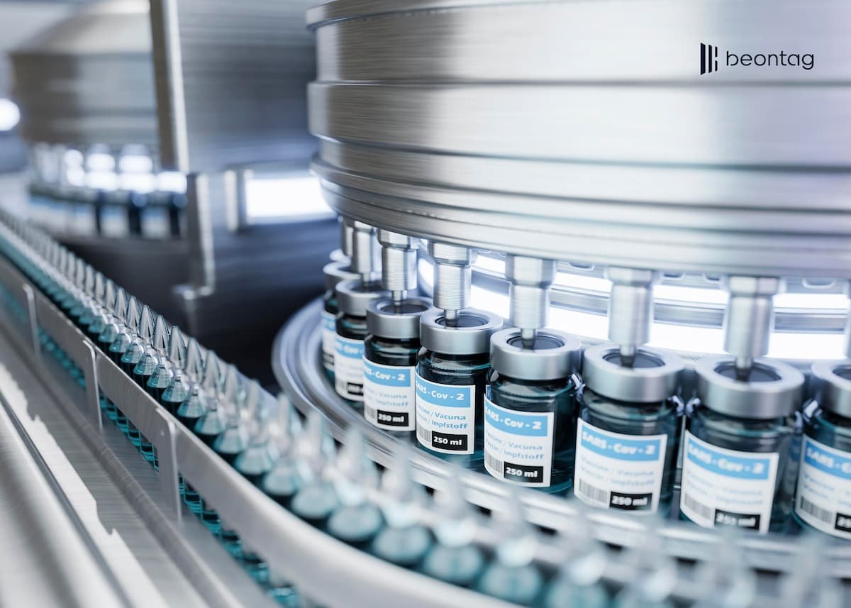Pharmaceutical vials on an automated production line with self-adhesive labels applied during high-speed filling and packaging.