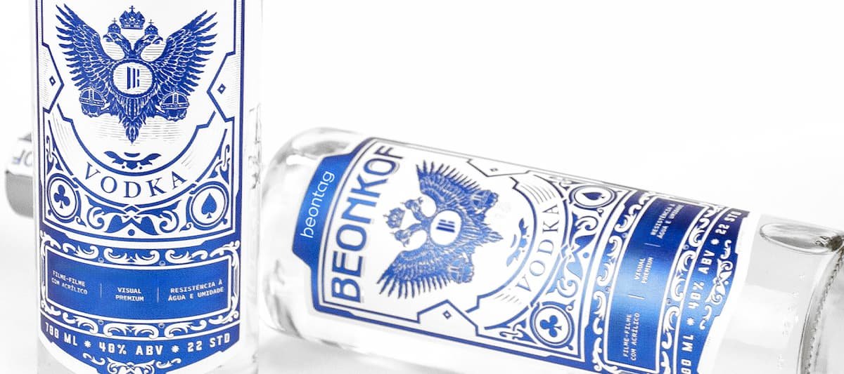 Garrafas de vodka transparentes com rótulos azuis ornamentados “BEONKOF”, logotipo de águia bicéfala e tipografia em destaque, sobre fundo branco.