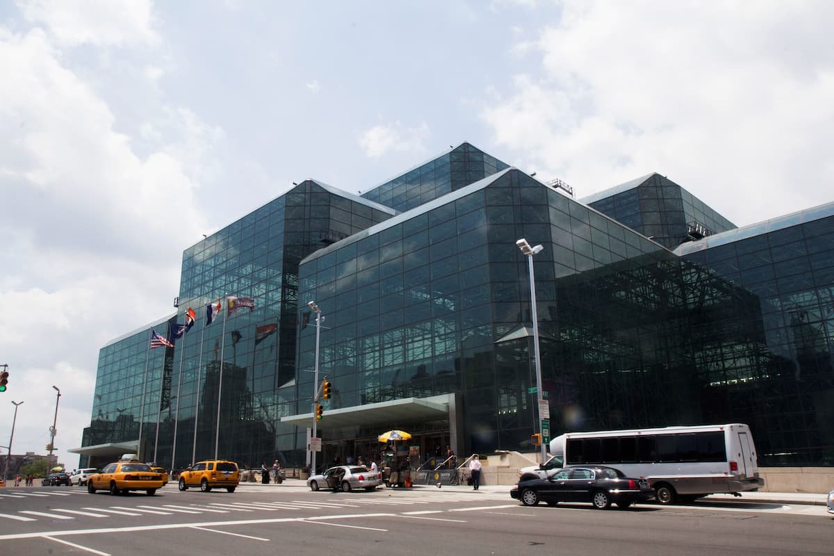 Glass-front convention center with flags and taxis outside, representing the venue and atmosphere of NRF 2026.