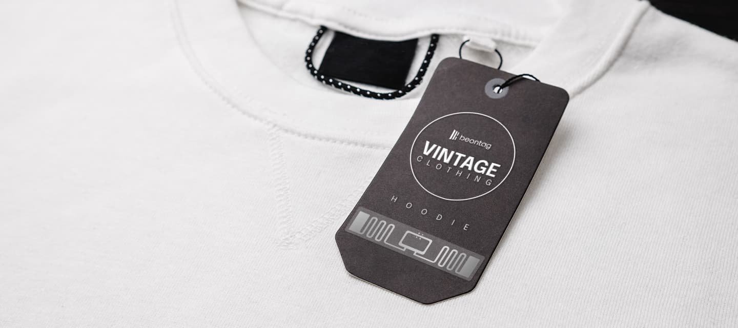 Close-up of a white hoodie with a black hang tag labeled “Beontag Vintage Clothing – Hoodie,” showing branding and product identification.
